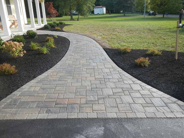 walkway of stone pavers leading to front of house with landscape and grass
