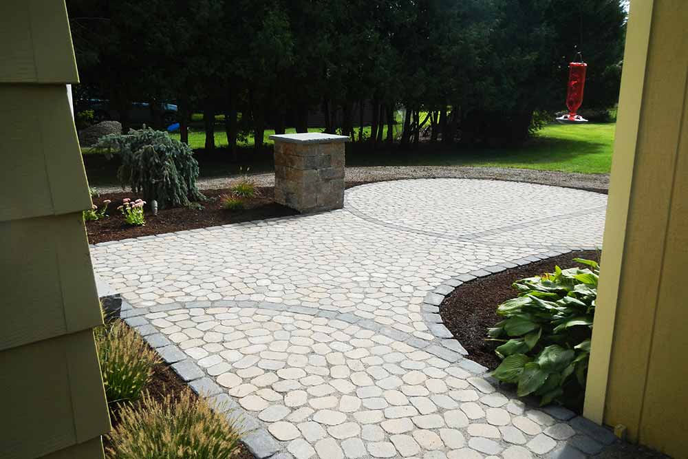 stone paver patio with hummingbird feeder and plants