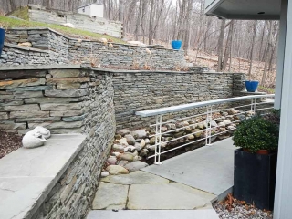 two level stone wall with sidewalk