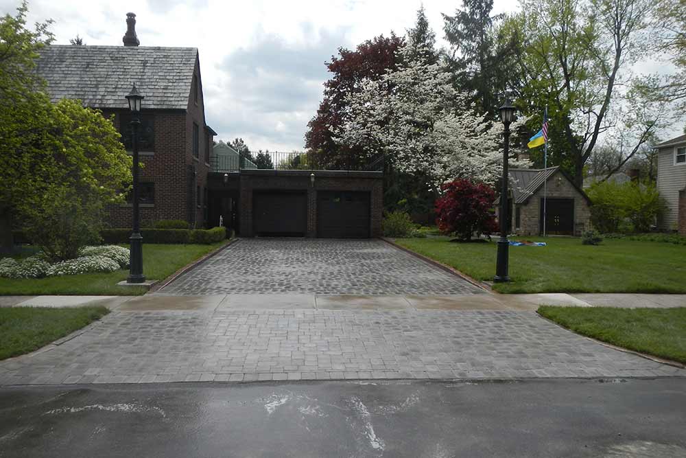 stone driveway with brick house and trees