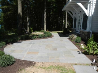small stone patio in back of house with trees